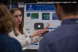 一名女主要研究学生在2018年跨学科科学期间展示她的海报 & 主要研究工程研讨会