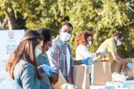 图为一群非营利组织工作人员在食品募捐活动中装满食品袋.