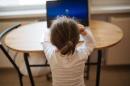 一个小孩坐在桌子旁在电脑前工作的照片.